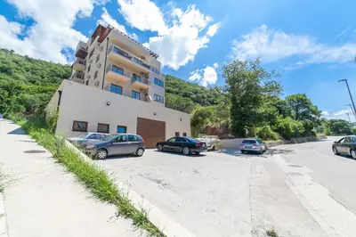 a building with cars parked in a parking lot at Welcome Apartments in Petrovac na Moru