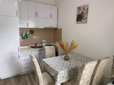 a kitchen with a table and chairs and a kitchen with white cabinets at Apartment Dragan in Budva
