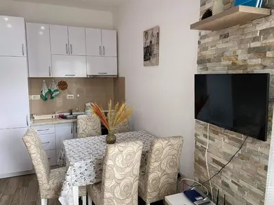 a kitchen with a table with chairs and a television at Apartment Dragan in Budva