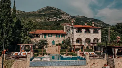 a house with a swimming pool in front of a mountain at Talići Hill - Rustic Villas in Sutomore