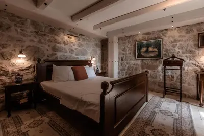 a bedroom with a bed and a stone wall at Talići Hill - Rustic Villas in Sutomore