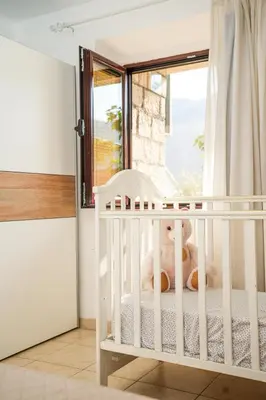 a white crib in a room with a window at Apartments Bućin in Kotor
