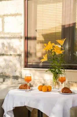 a table with two plates of food and a vase with yellow flowers at Apartments Bućin in Kotor
