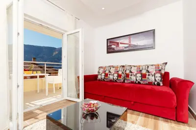 a red couch in a living room with a balcony at Apartments Blue Sea in Kotor