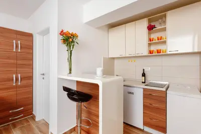 a kitchen with white cabinets and a counter with a vase of flowers at Apartments Blue Sea in Kotor