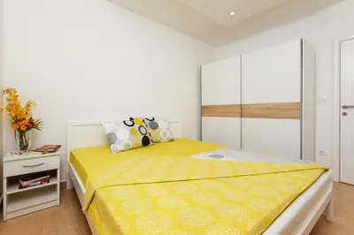 a bedroom with a yellow bed and a white cabinet at Apartments Blue Sea in Kotor