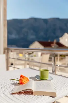 a book and a cup and a rose on a table at Apartments Blue Sea in Kotor