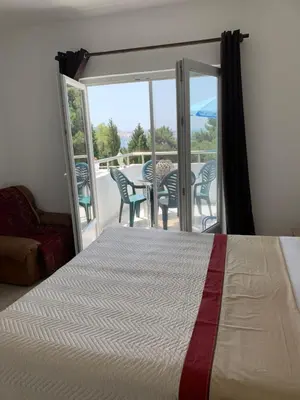 a bedroom with a bed and a balcony with a table and chairs at Apartments Ljiljana in Bar