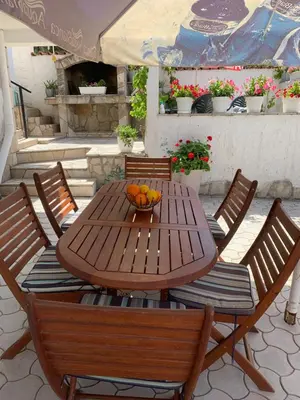 a wooden table with chairs and a bowl of oranges on it at Apartments Ljiljana in Bar