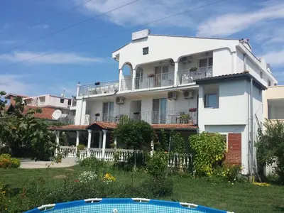 a white house with a balcony and a swimming pool at House Kraja in Ulcinj