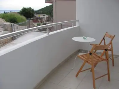 a wooden chair sitting on a balcony with a table at Apartmani Vukmanovic in Čanj