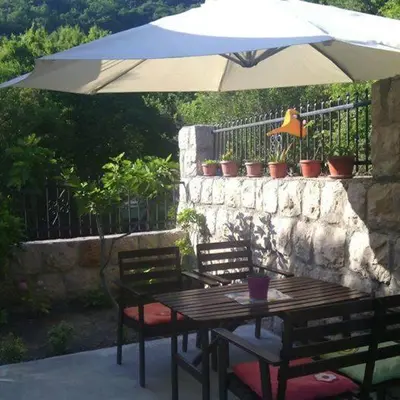 a table and chairs with an umbrella on a patio at Apartmani Vukmanovic in Čanj