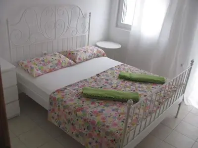 a white bed with two green pillows on it at Apartmani Vukmanovic in Čanj