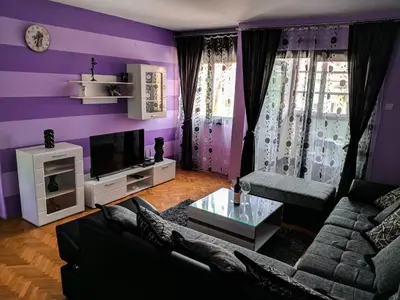 a purple living room with a couch and a tv at Apartment Branka in Budva