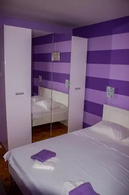 a purple and white bedroom with a bed and a mirror at Apartment Branka in Budva