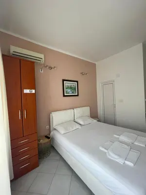 a bedroom with a large white bed and a cabinet at Apartments SoleMar2 in Sutomore