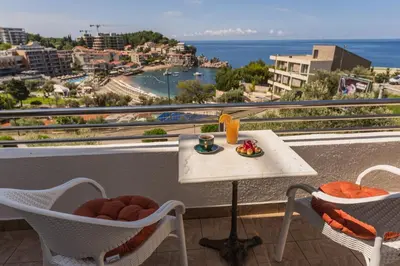 a table and chairs on a balcony with a view of the ocean at Apartments Raymond in Sveti Stefan
