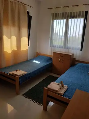 a room with two beds and a table and windows at Villa Persik in Utjeha