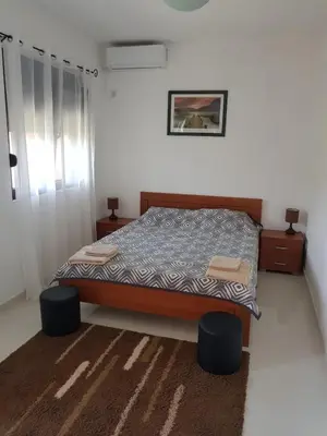 a bedroom with a bed with two ottomans and two tables at Villa Persik in Utjeha