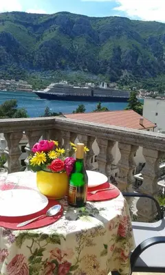 a table with a bottle of wine and flowers on a balcony at Apartment Ivan in Kotor