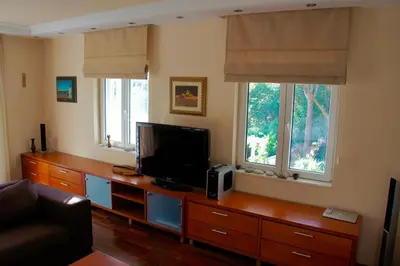 a living room with a tv and two windows at Cezar Holiday Home in Sveti Stefan