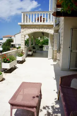 a patio with benches and a balcony with a staircase at Cezar Holiday Home in Sveti Stefan