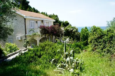 a house on the side of a hill with a garden at Cezar Holiday Home in Sveti Stefan
