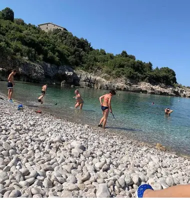 a group of people playing in the water on a rocky beach at Apartment Ema Star in Utjeha
