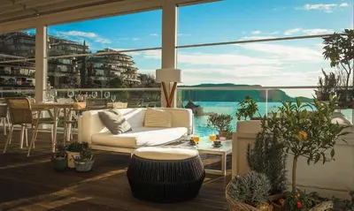a patio with a white couch and a table and some plants at Dukley Hotel & Resort in Budva
