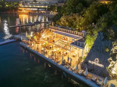 an aerial view of a restaurant on the water at night at Dukley Hotel & Resort in Budva