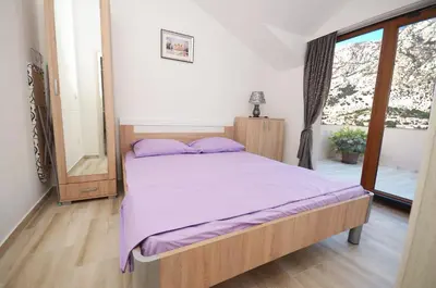 a bedroom with a bed with purple sheets and a window at Apartmani Mizdrak in Kotor