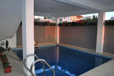 a swimming pool with a chair next to a building at Apartments Stevanović in Dobra Voda