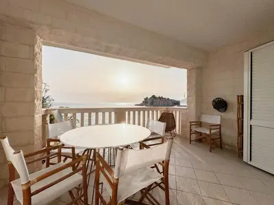 a table and chairs on a balcony with a view of the ocean at Apartment Radovic in Sveti Stefan