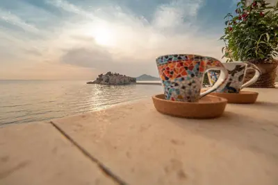 two cups sitting on a ledge near the water at Apartment Radovic in Sveti Stefan