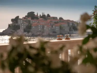 two coffee cups sitting on a ledge with a castle in the background at Apartment Radovic in Sveti Stefan