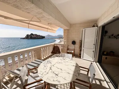 a balcony with a table and chairs and the ocean at Apartment Radovic in Sveti Stefan