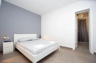a white bedroom with a bed and a walk in shower at Apartments Mika in Budva