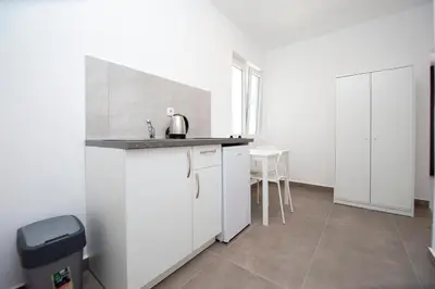 a white kitchen with a sink and a table at Apartments Mika in Budva