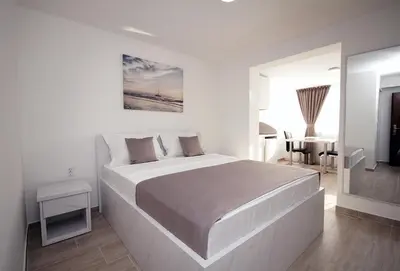 a white bedroom with a large bed and a table at Apartments Residence Dj in Petrovac na Moru