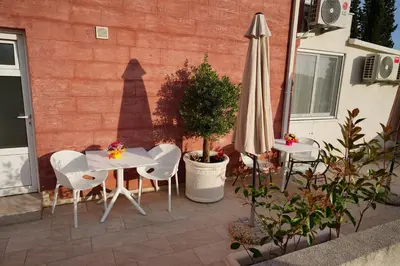 a patio with an umbrella and two tables and chairs at Apartments Residence Dj in Petrovac na Moru