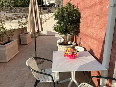 a white table and chairs with flowers on a patio at Apartments Residence Dj in Petrovac na Moru