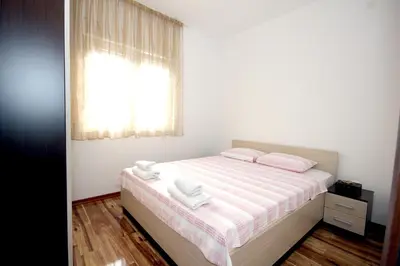 a bedroom with a bed with pink sheets and a window at Apartments Residence Dj in Petrovac na Moru