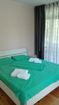 a bedroom with a bed with green sheets and towels at Villa Nadija in Čanj