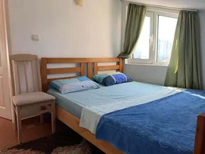 a bedroom with a bed and a chair and a window at Korolev Apartment in Budva