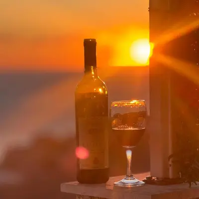 a bottle of wine and a glass at sunset at Apartman Aleksandar in Ulcinj