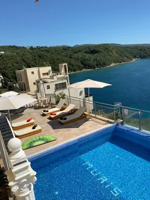 a swimming pool with chairs and umbrellas next to the water at Villa Apartmani Anja in Dobra Voda