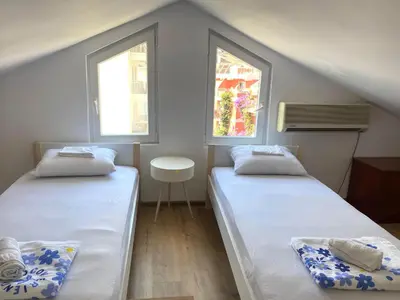 two beds in a small room with two windows at Apartment Talas in Budva