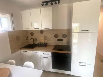 a kitchen with white cabinets and a black dishwasher at Apartment Talas in Budva