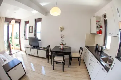 a kitchen and living room with a table and chairs at Apartments Lumiere in Rafailovici