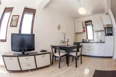 a kitchen with a table with a tv and a dining room at Apartments Lumiere in Rafailovici